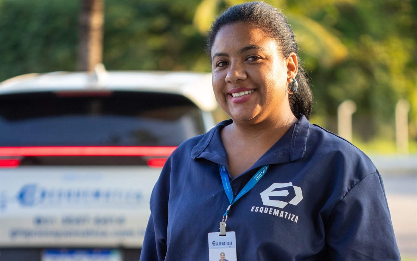 Auxiliar de serviços gerais da Esquematiza uniformizada, sorrindo, em local de operação.