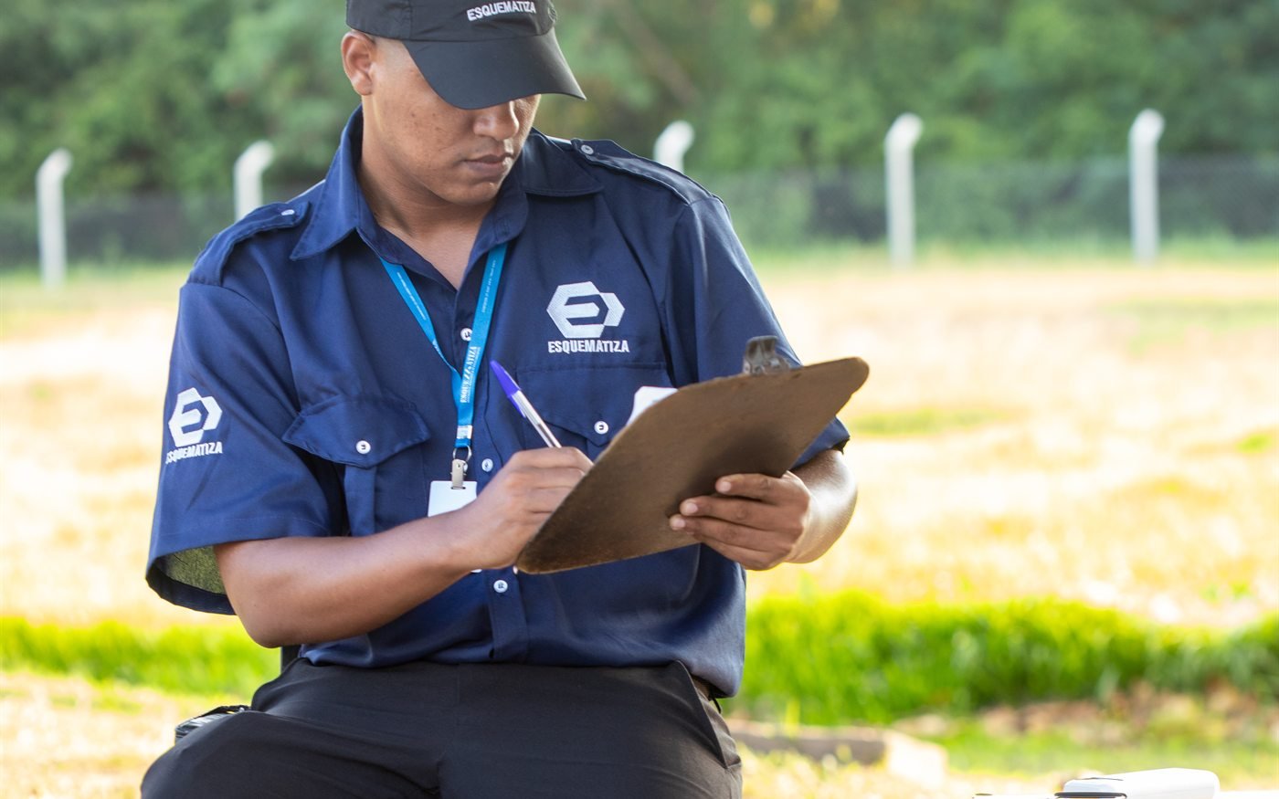 Profissional da Esquematiza registrando informações em prancheta durante controle de acesso.