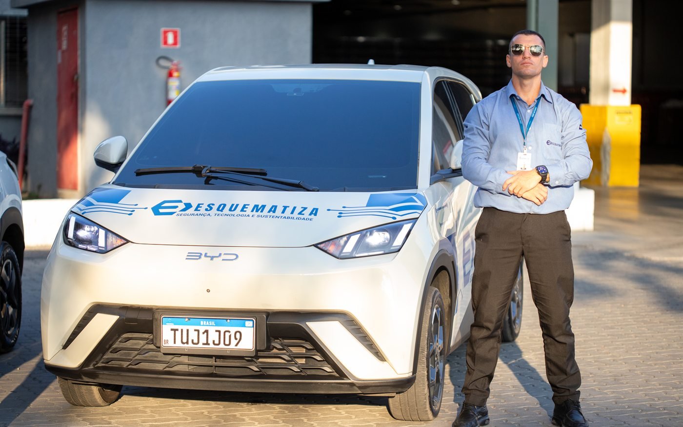 Agente da Esquematiza ao lado de viatura elétrica da frota.