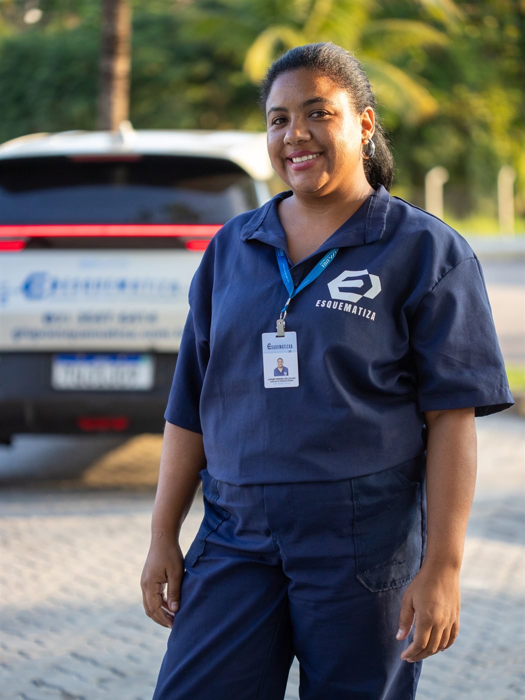 Colaboradora da Esquematiza uniformizada, sorrindo, em local de operação.