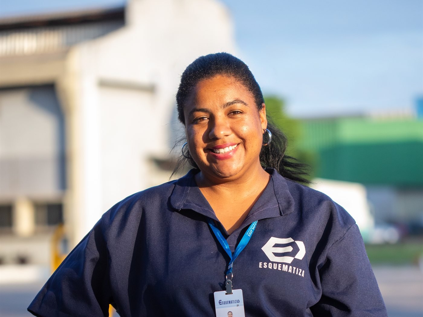 Auxiliar de serviços gerais da Esquematiza uniformizada, sorrindo, em local de operação.