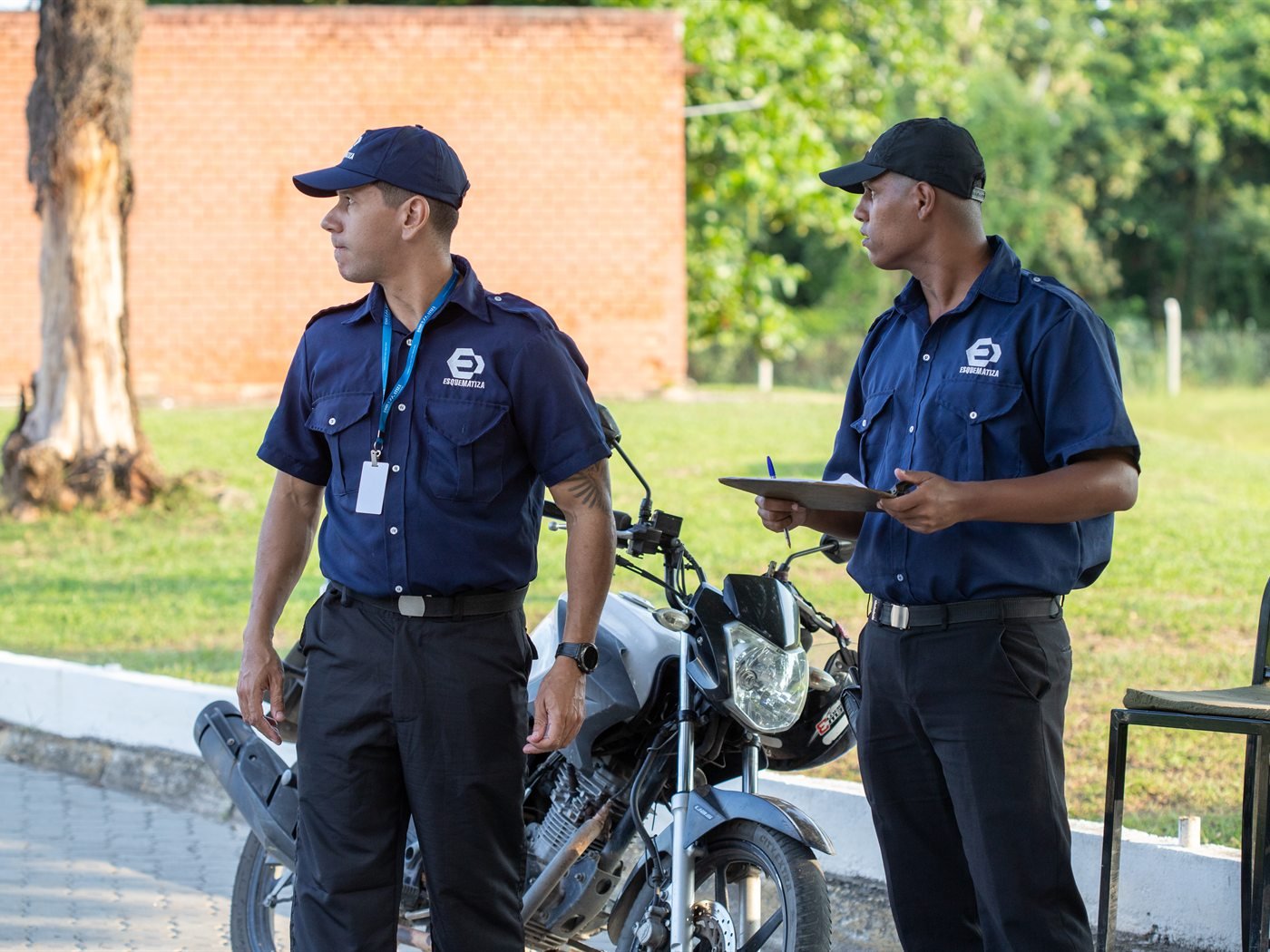 Dois agentes da Esquematiza em serviço, um deles conferindo a prancheta de ronda.