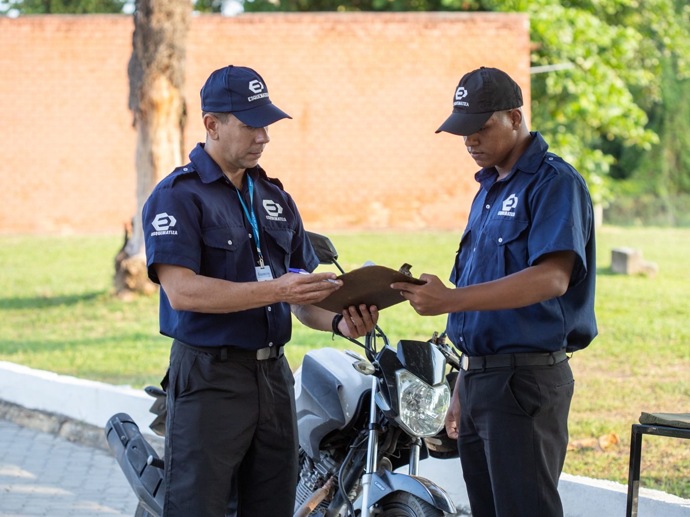 Dois agentes da Esquematiza conferindo informações em prancheta durante o turno.